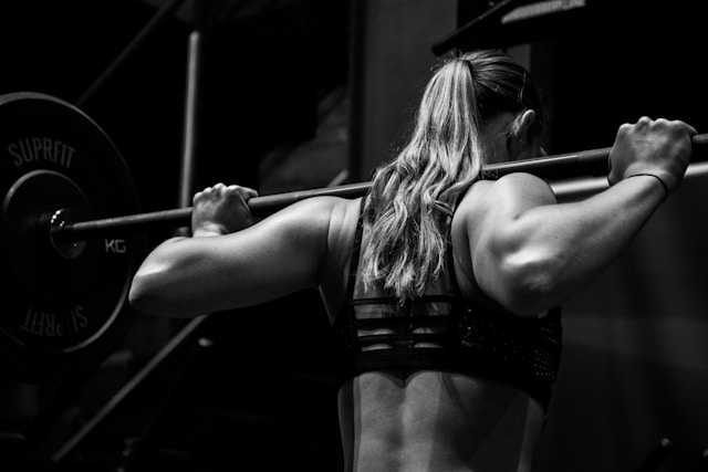 Grayscale photo of woman lifting barbell