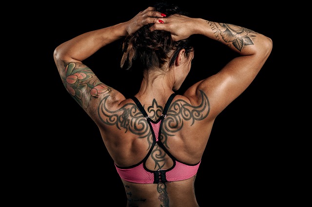 Tattooed muscle woman showing her back and holding her hair up